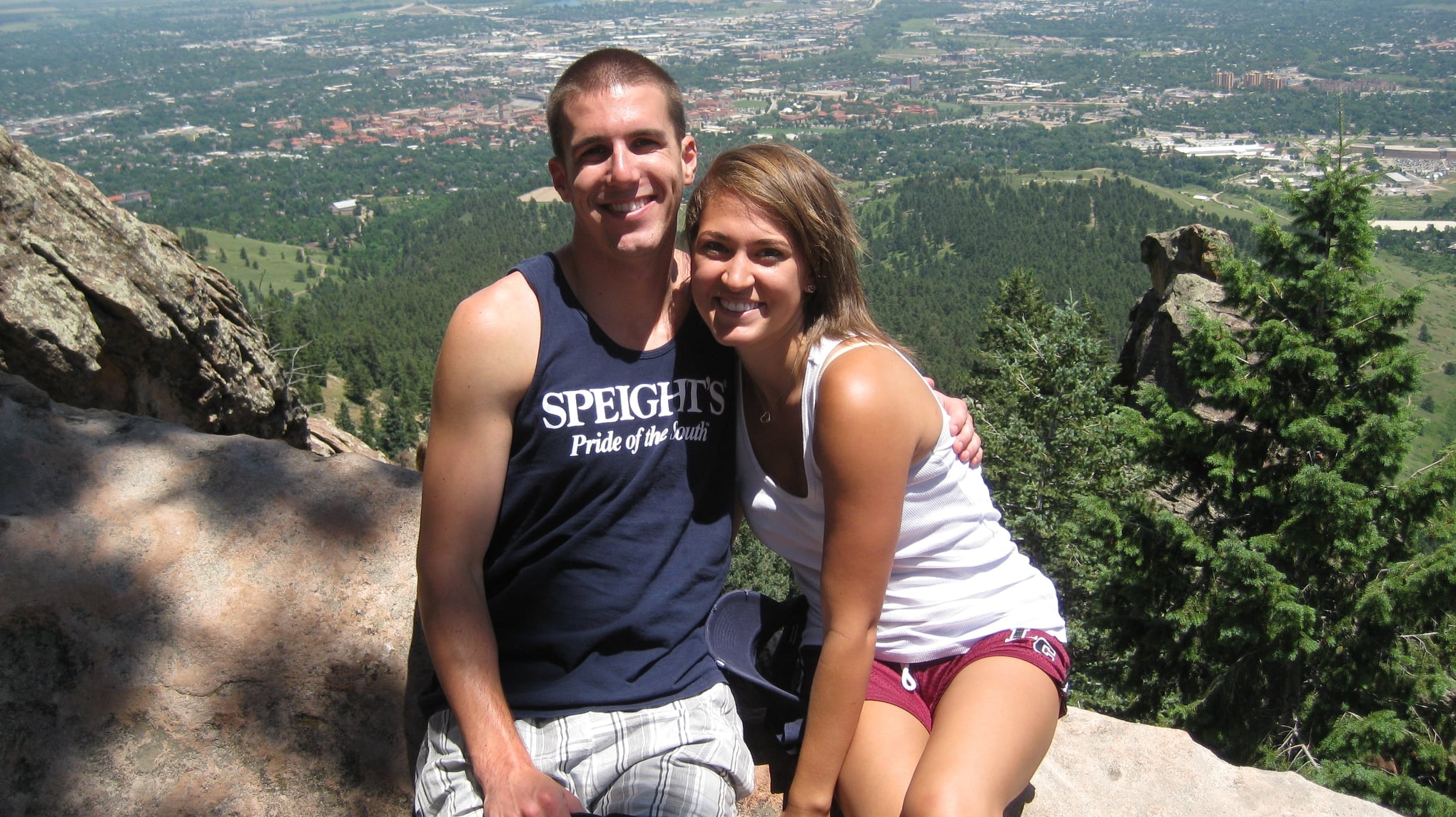 Alex & Breauna Kanzler posing on a rocky outcrop with a scenic landscape in the background