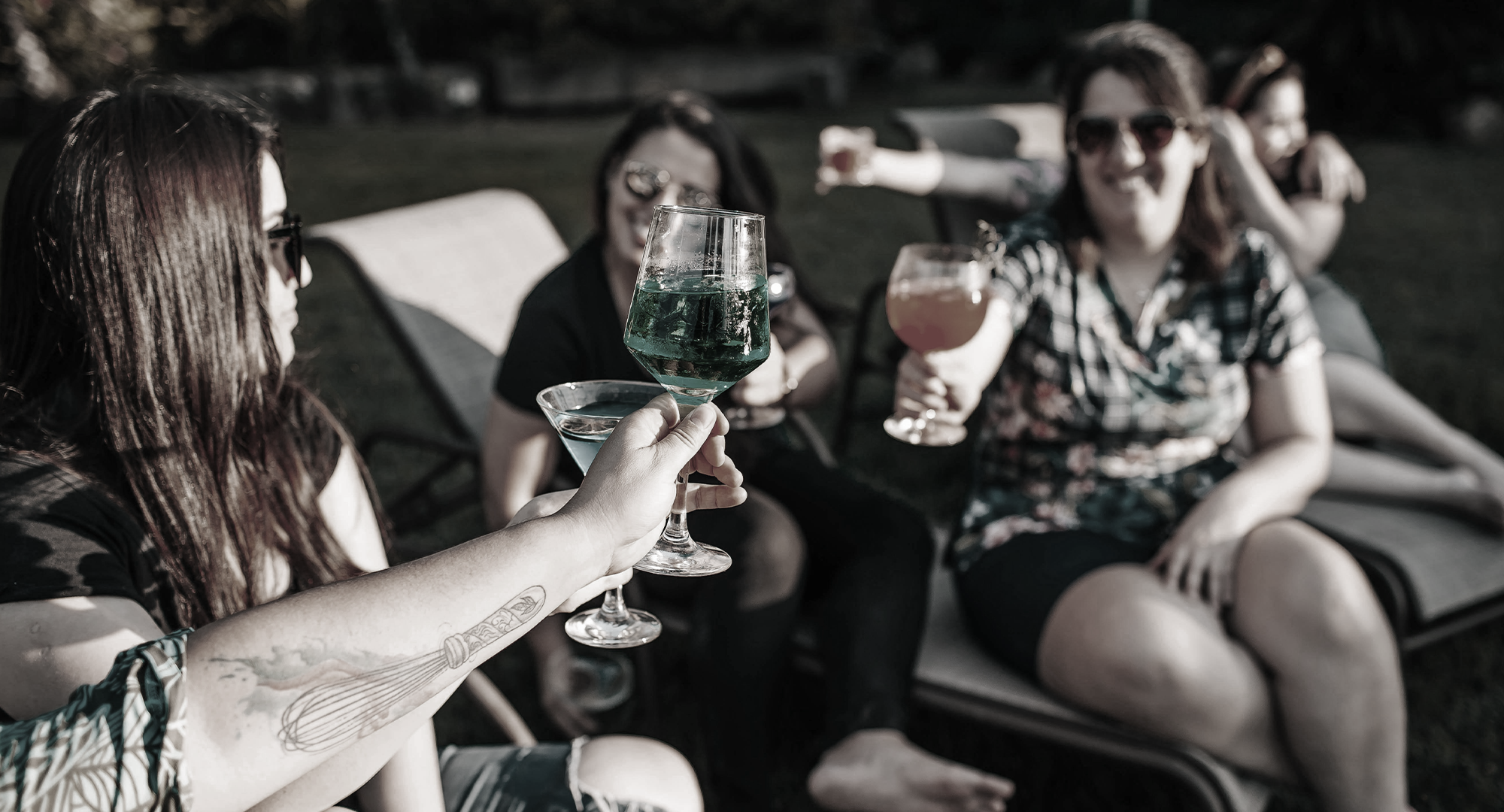 Group of people sitting outdoors, toasting with drinks.